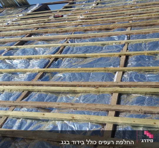 קורות עץ על גג עם בידוד מתכתי מבריק